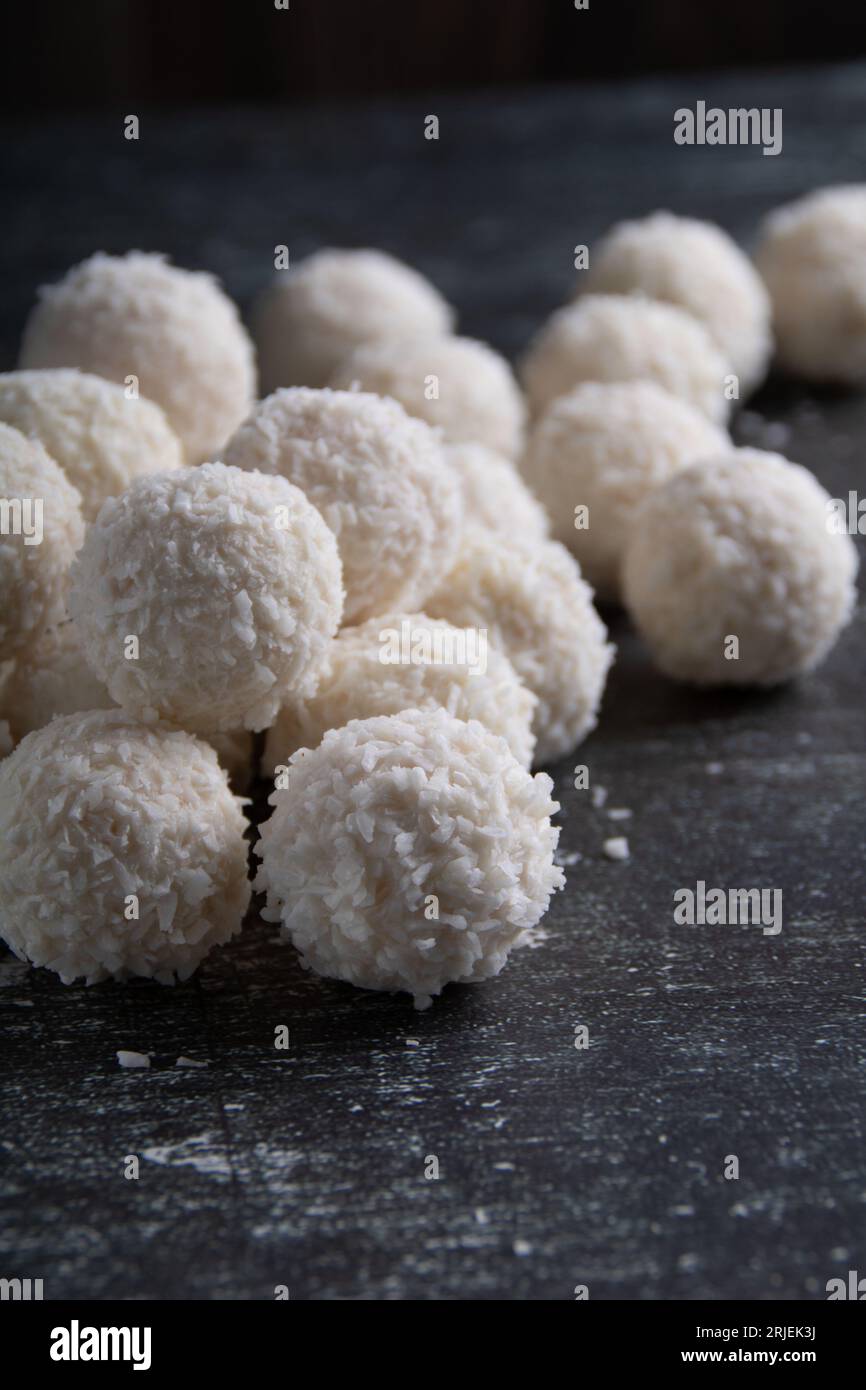 Foto viele weiße Schokolade Kokosnussbonbons liegen auf dem Tisch, Nahaufnahme. Dessert süßes Essen, Zucker, auf Holzbrett, leerer Platz Stockfoto