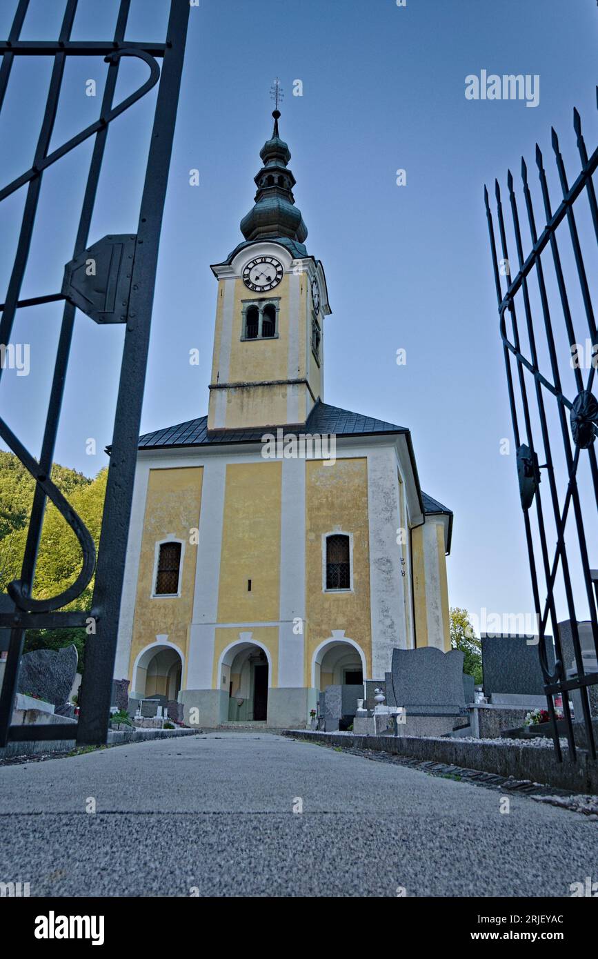 Sehr alte gelbe traditionelle europäische Architekturkirche auf dem Hügel in Srednja Vas V Bohinju in der Nähe des Bohinjer Sees. Nationalpark Triglav. Slowenien. Stockfoto