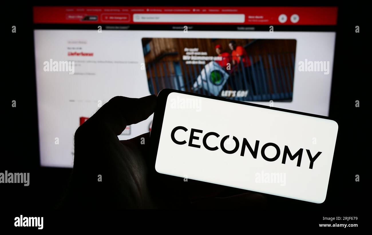 Person, die ein Mobiltelefon mit dem Logo des deutschen Einzelhandelsunternehmens CECONOMY AG auf dem Bildschirm vor der Business-Webseite hält. Konzentrieren Sie sich auf das Display des Telefons. Stockfoto