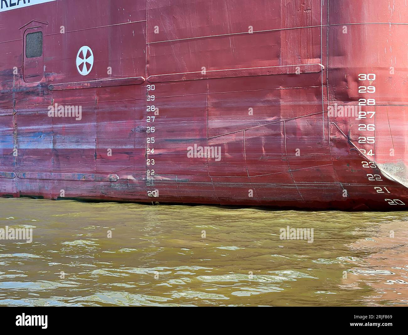 Plimsoll-Linienmarkierungen auf dem Rumpf eines Frachters in grünem Wasser Stockfoto