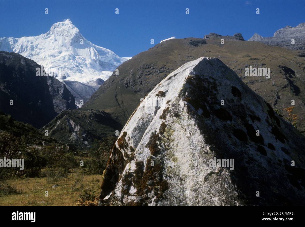 Peru, Andengebirge - Cordillera de los Andes, Cordillera Blanca. Schneebedeckter Berg Huandoy (6395 m) mit Felsbrocken im Vordergrund Stockfoto