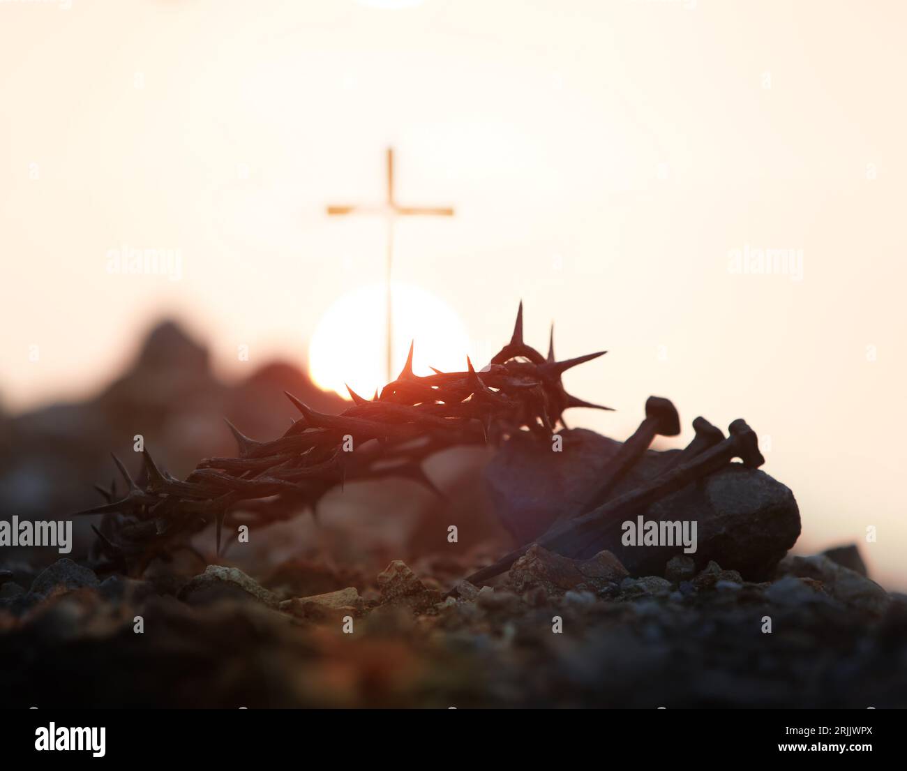 Das Kreuz, die Dornenkrone, die Nägel und der rote Sonnenuntergang symbolisieren das Opfer und das Leiden von Jesus Christus, die Leidenswoche und das Konzept der Leihgabe Stockfoto