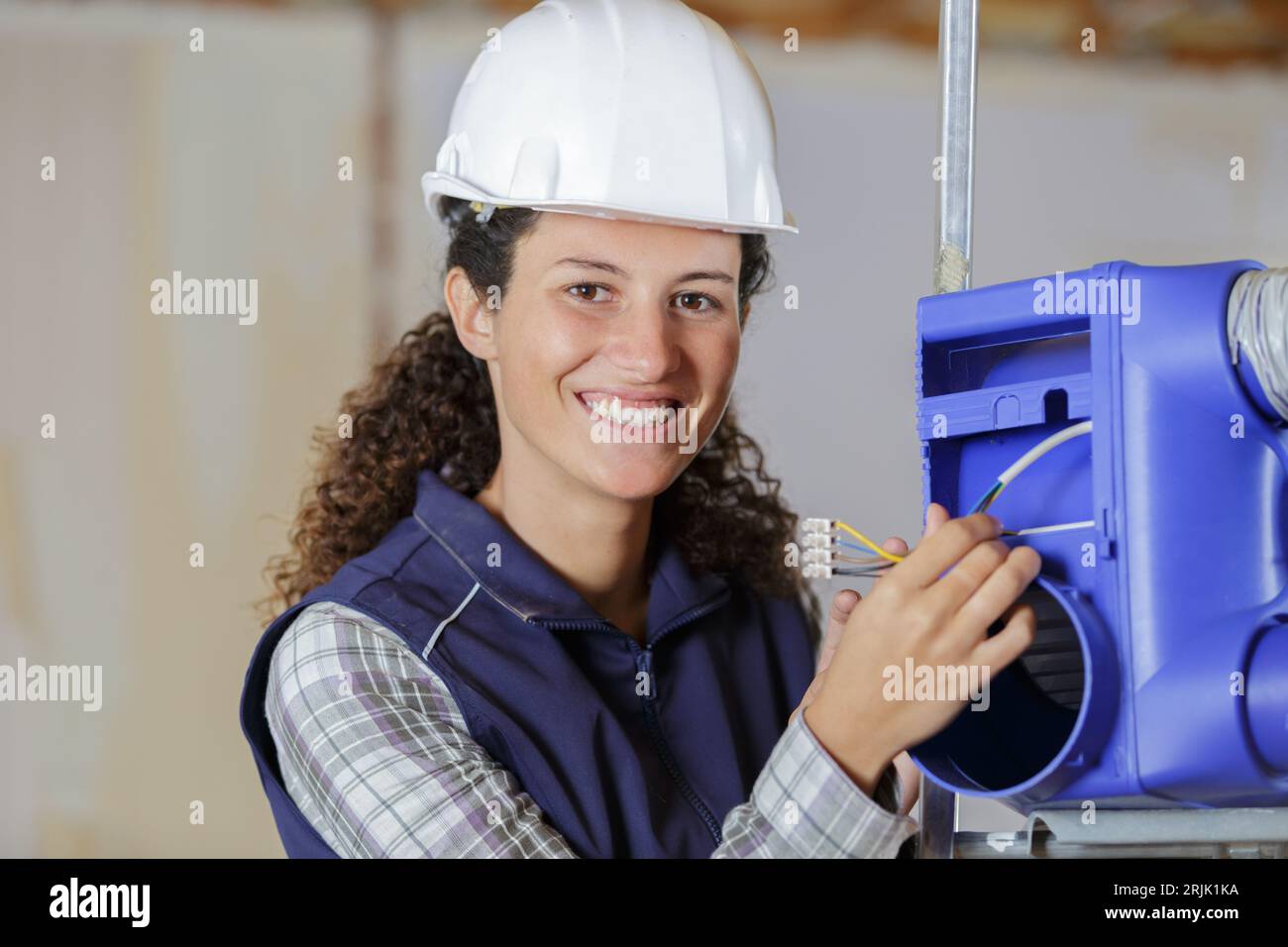 Weibliche Bauherrin, die einen Lüftungskasten installiert Stockfoto