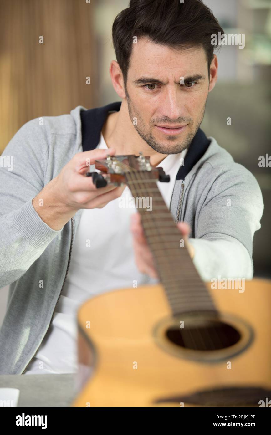 Zimmermann inspiziert in der Werkstatt einen hölzernen Gitarrenhals Stockfoto