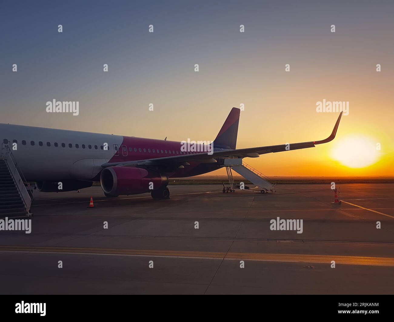 Flugzeug bereit zum Einsteigen am Flughafen mit Blick auf den Sonnenaufgang. Reise- und Urlaubskonzept Stockfoto