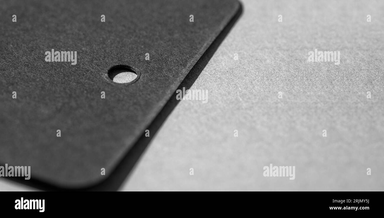 Hängen Sie das Mock-up für das Branding-Etikett auf einen grauen Tisch. Stehende schwarz-weiße Tags. Stockfoto