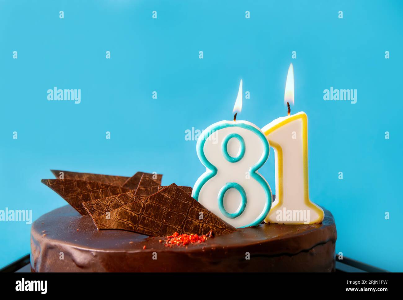 Nummer 81 Geburtstagskerze brennt auf Kuchen. Das 80er-Geburtstagsfest oder Jubiläumskonzept. Viel Platz für Kopien auf blauem Hintergrund. Stockfoto