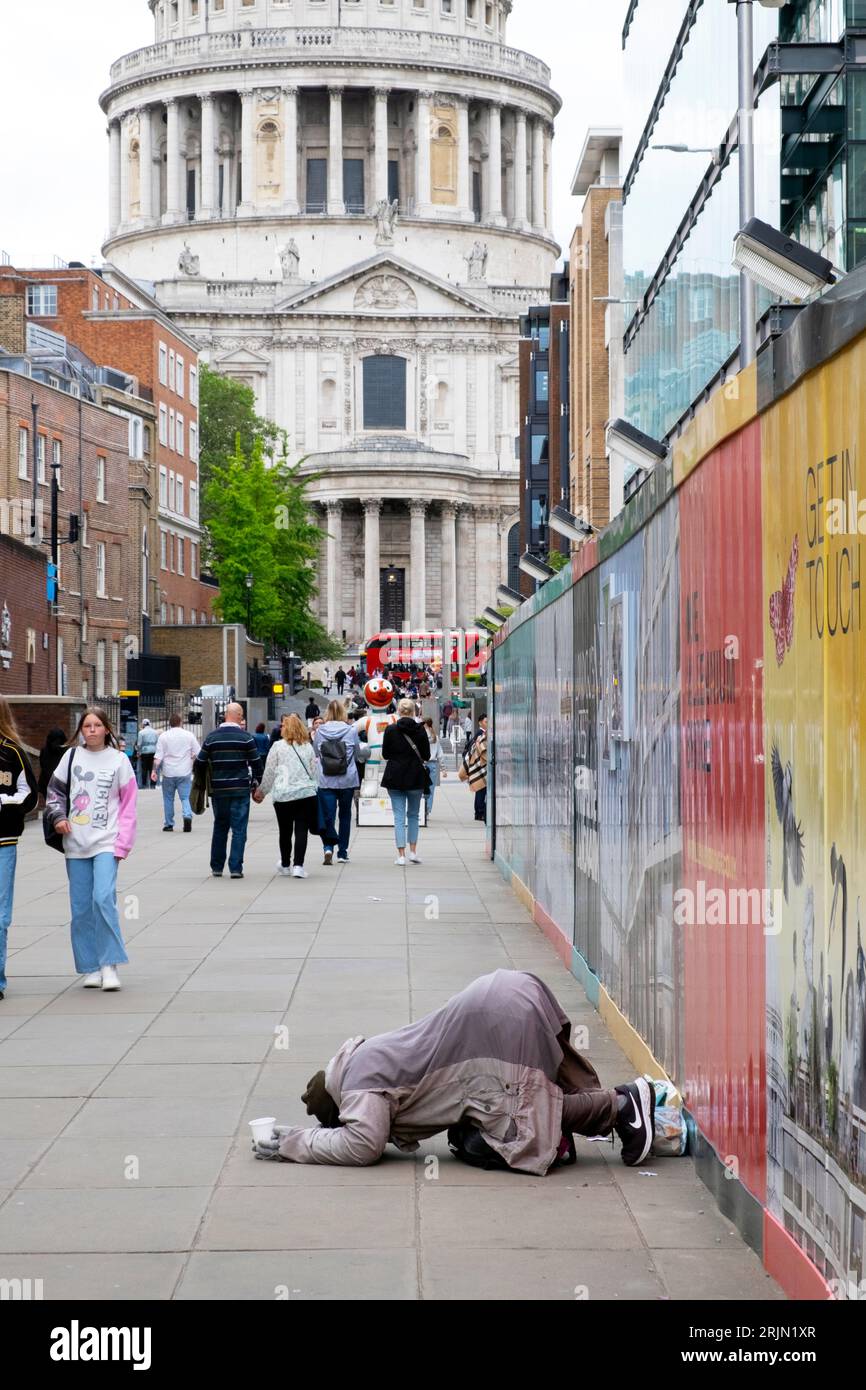 Obdachloser Mann, der auf der Straße bettelte und sich auf dem Bürgersteig in der Nähe der St Pauls Cathedral in der City of London, England, Großbritannien, 2023 KATHY DEWITT niederkniete Stockfoto