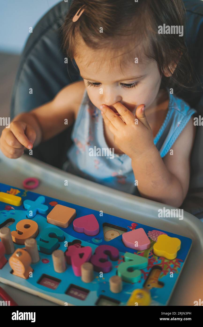 Lifestyle-Porträt eines Kleinkindes, das mit Holzfiguren spielt, Formen und Farben lernt. Pädagogisches Konzept. Farbenfroher Holzblock geometrisch Stockfoto