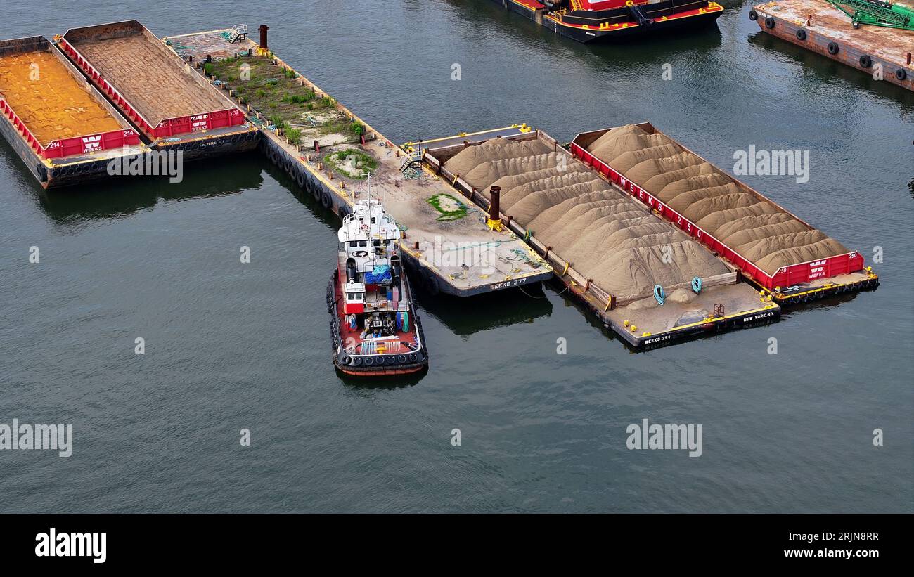 Ein Lastkahn dockte in der Nähe eines schwimmenden Docks in einem mit einer großen Menge Sand gefüllten Gewässer an Stockfoto