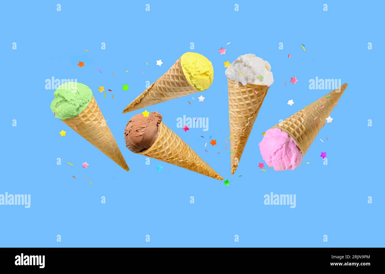 Eislöffel in Waffelkegeln fliegen auf blauem Hintergrund. Stockfoto