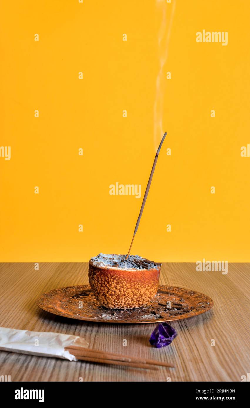 Ein vertikaler Abschluss eines brennenden Räucherstäbchens in getrockneter halbierter Orange Stockfoto