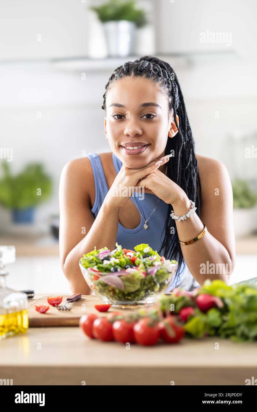 Ein gut aussehendes Afro-amerikanisches Mädchen bereitete einen gesunden gemischten Salat mit frischem Gemüse zu. Stockfoto