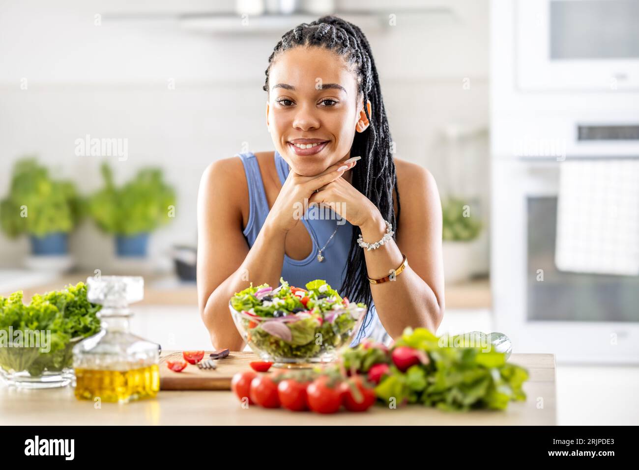 Ein gut aussehendes Afro-amerikanisches Mädchen bereitete einen gesunden gemischten Salat mit frischem Gemüse zu. Stockfoto