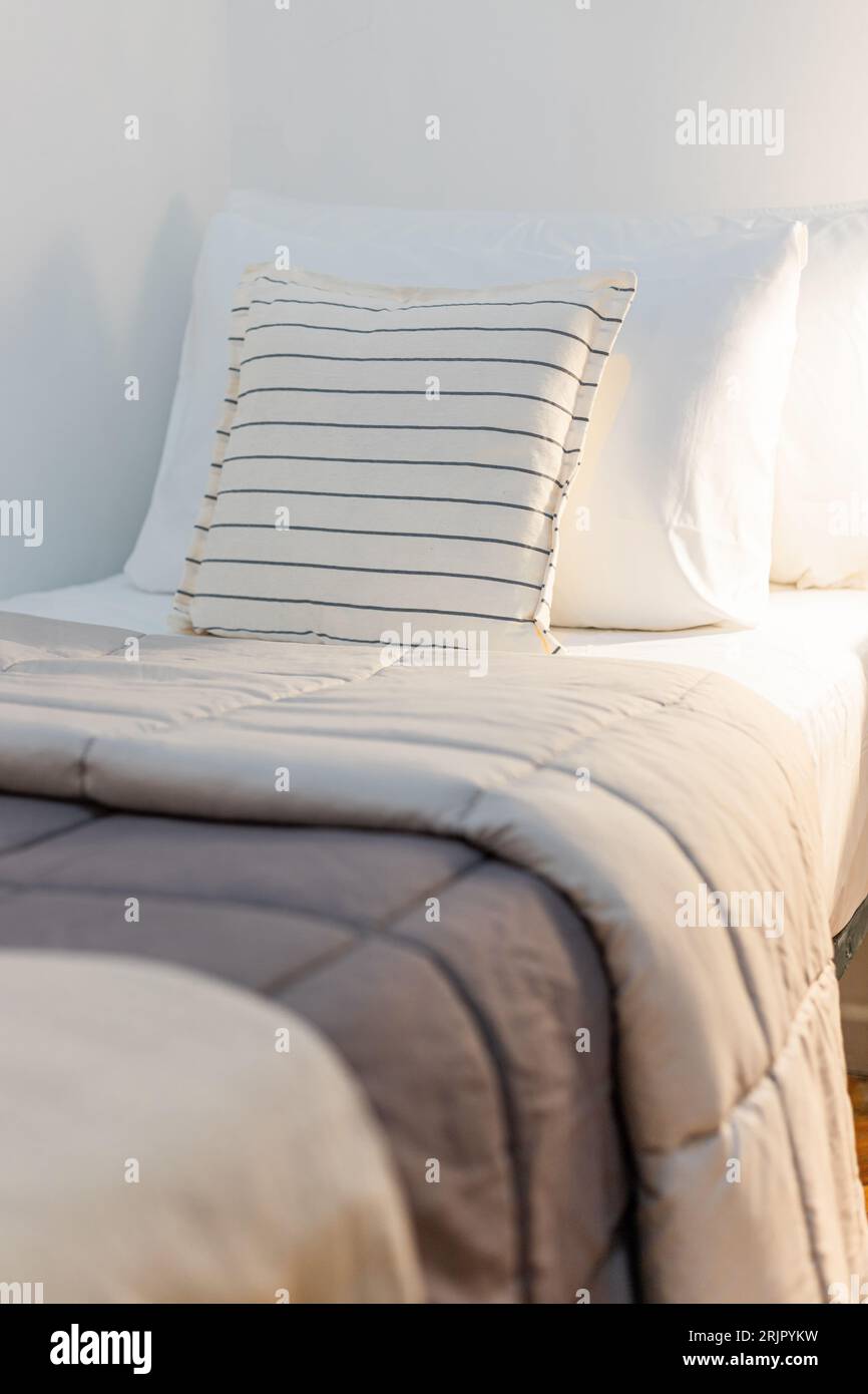 Gemütliches Bett mit braunen und hellbeigen Bettdecken und weißen Kissen Stockfoto
