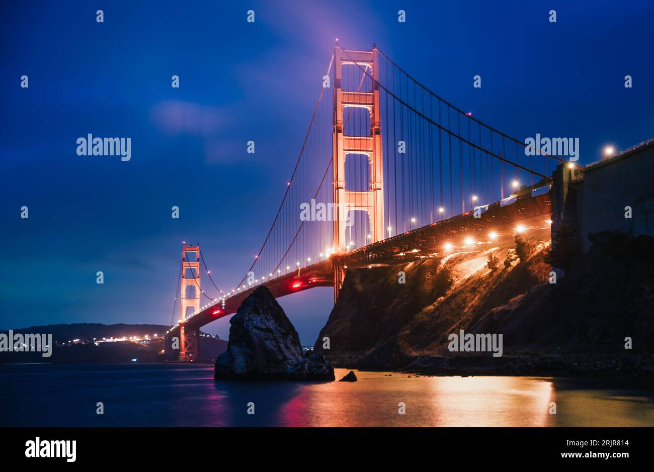 Ein atemberaubender nächtlicher Blick auf die weltberühmte Golden Gate Bridge, beleuchtet vor der Kulisse von dunkelblauem Wasser Stockfoto