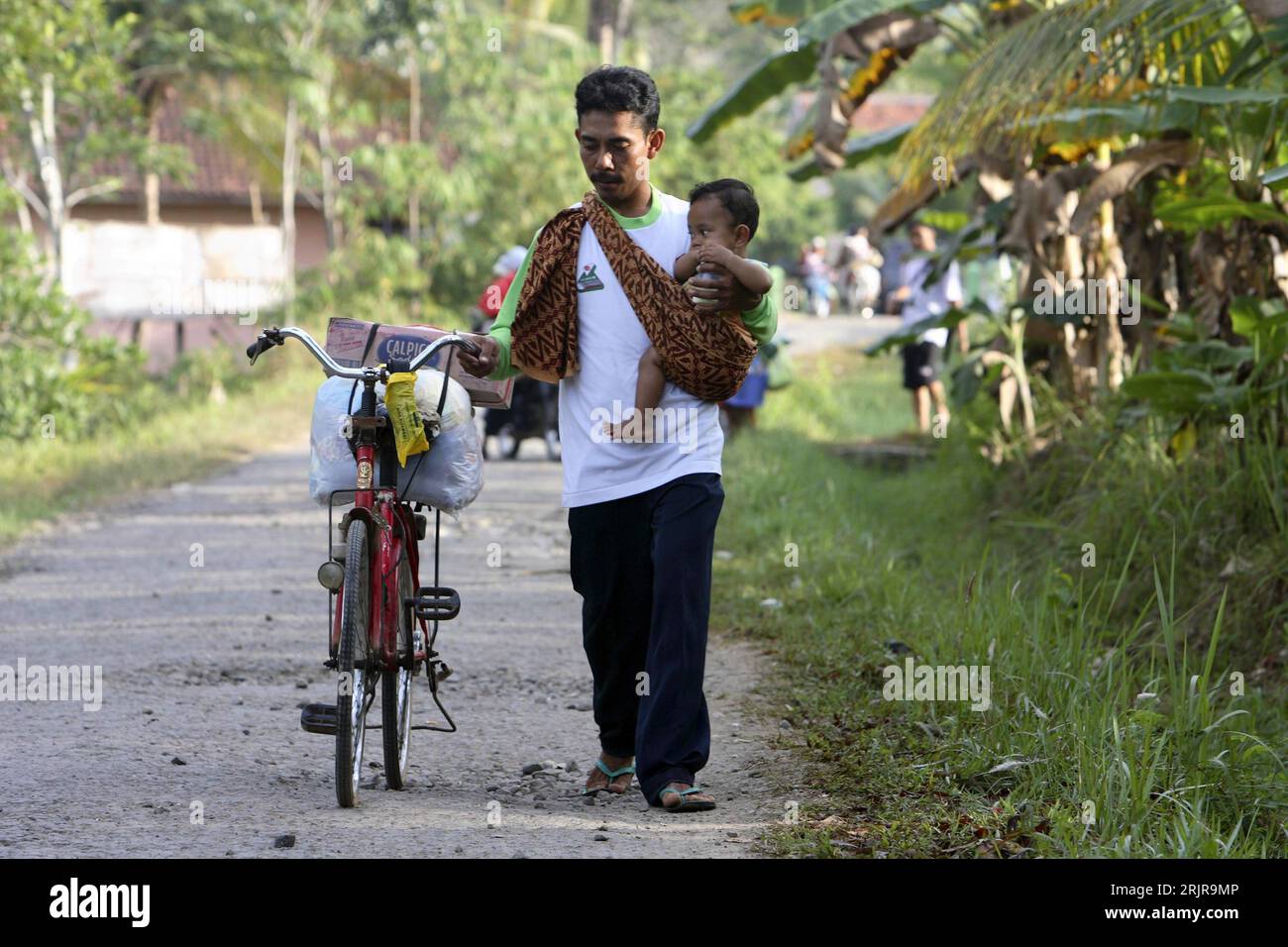 Bildnummer: 51347376 Datum: 23.07.2006 Copyright: imago/Xinhua Flüchtling mit einem Baby auf dem Arm und seinem Fahrrad nach dem verheerenden Tsunami in Pangandaran auf Java - PUBLICATIONxNOTxINxCHN, Personen; 2006, Pangandaran, Java, Mann, Männer, Flüchtlinge, Kind, Kleinkind, Kleinkinder, Naturkatastrophen, Katastrophe, Katastrophen, Indonesier, Opfer, Fahrräder, Rad, Räder; , quer, Kbdig, Gruppenbild, Indonesien, , Stockfoto