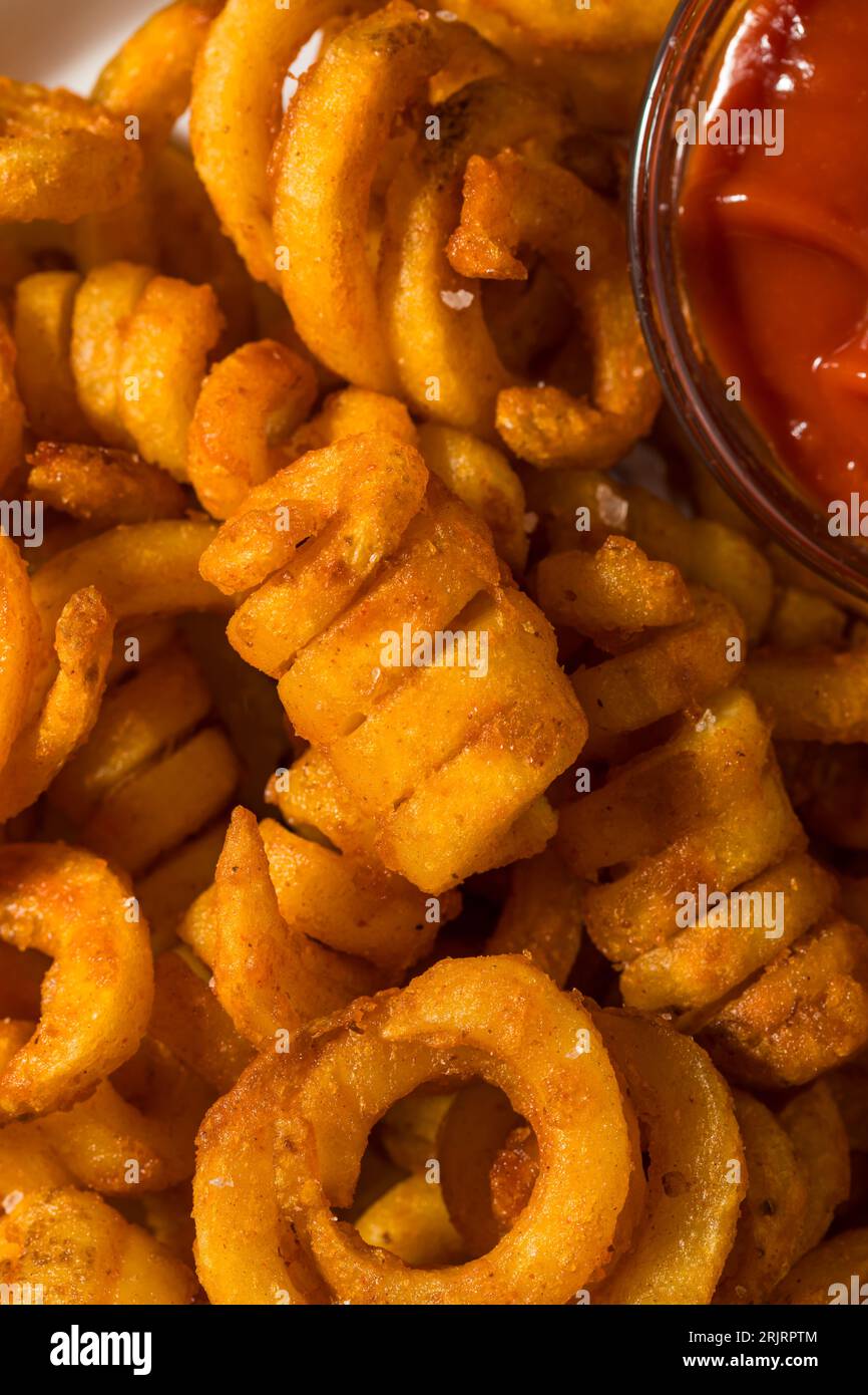 Gewürzte hausgemachte lockige Pommes Frites mit Ketchup Stockfoto