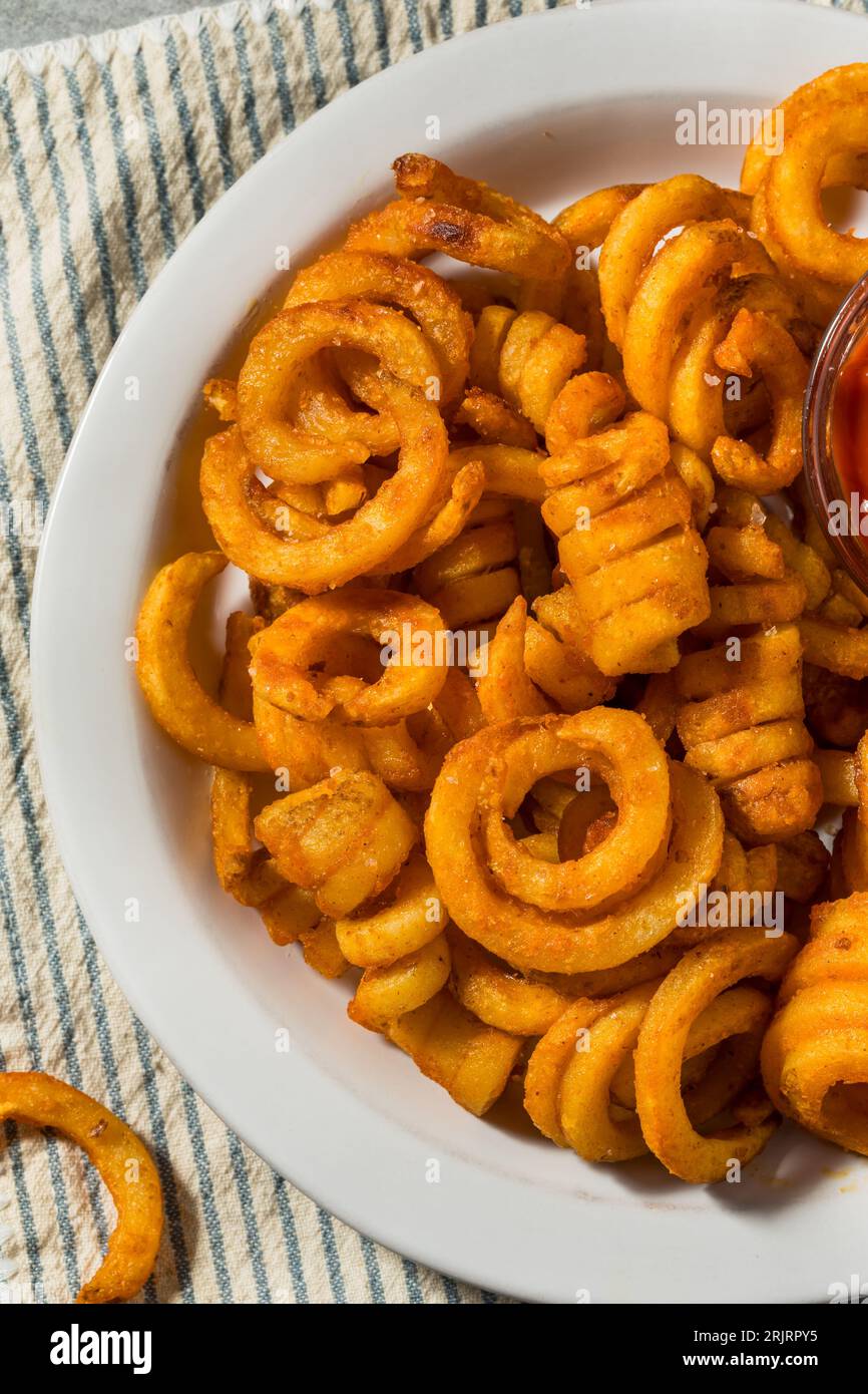 Gewürzte hausgemachte lockige Pommes Frites mit Ketchup Stockfoto