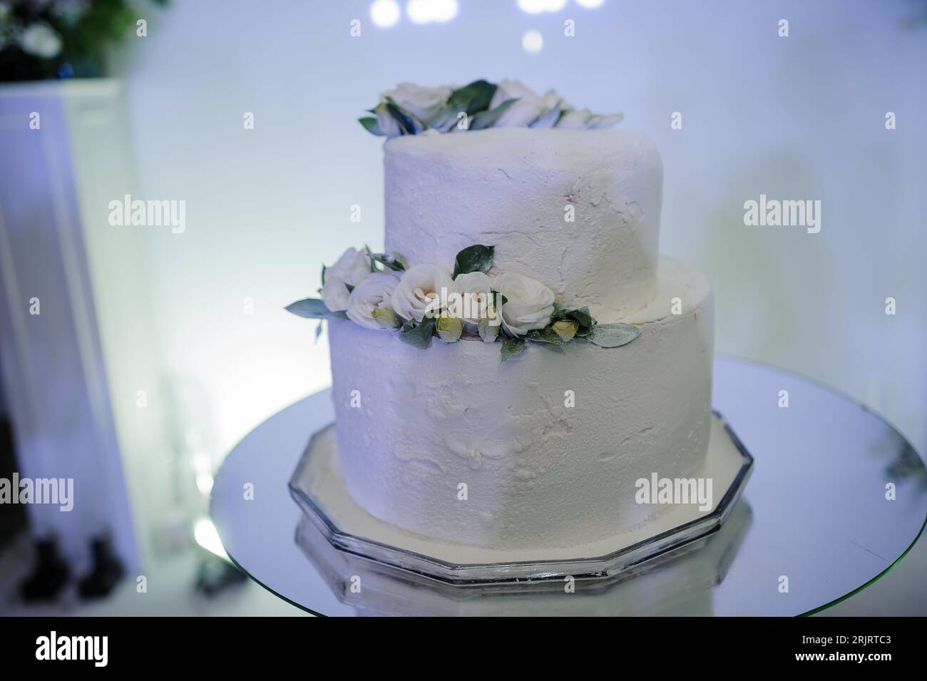 Wunderschöne Hochzeitstorte mit Blumen, Kuchengründung und verschwommenem Hintergrund Stockfoto