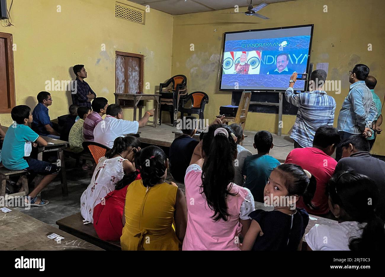 Barpeta, Indien. 23. August 2023. Premierminister Narendra Modi (C-Bildschirm) gratuliert der Indian Space Research Organisation (ISRO) zur erfolgreichen Mondlandung der Chandrayaan-3-Raumsonde auf dem Südpol des Mondes während eines Live-Streams der Veranstaltung in einer Schule in Barpeta, Assam, Indien am 23. August 2023. Quelle: David Talukdar/Alamy Live News Stockfoto