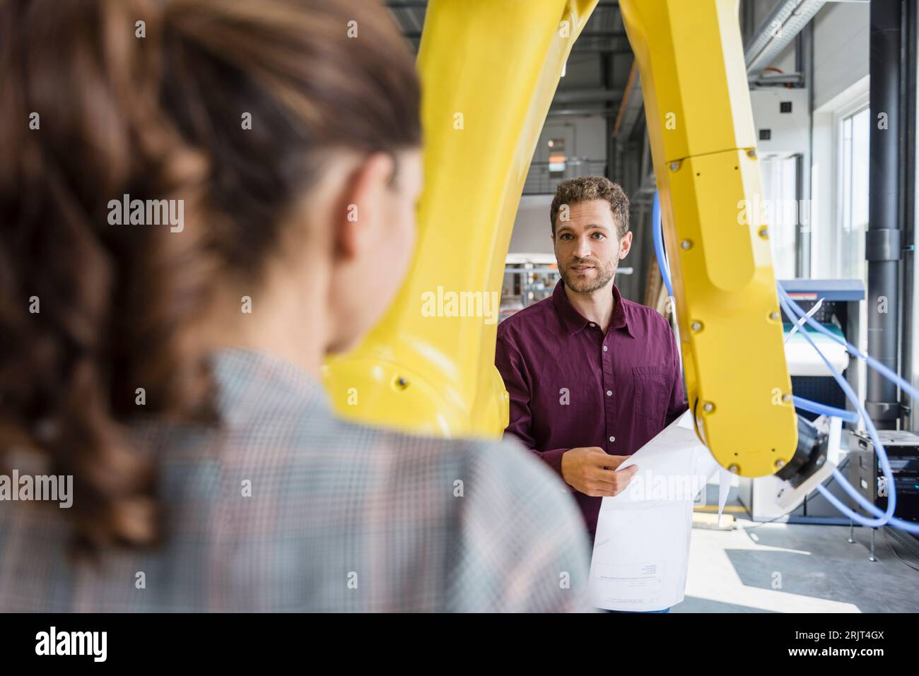 Kaufmann und Frau in einer Sitzung vor Industrieroboter in einem High-Tech-Unternehmen Stockfoto