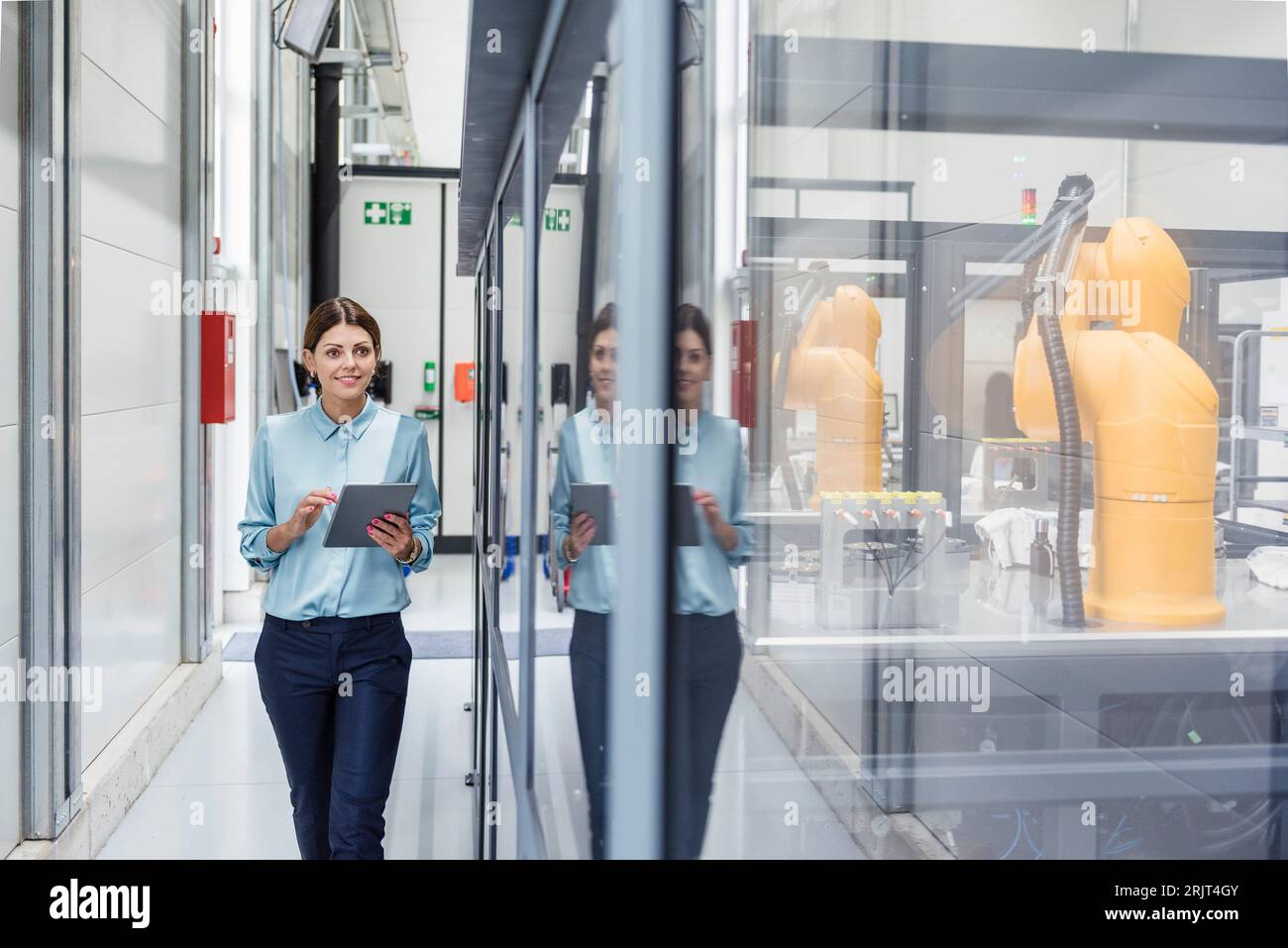 Geschäftsfrau Kontrolle Roboter mit digitalen Tablet in High-Tech-Unternehmen Stockfoto