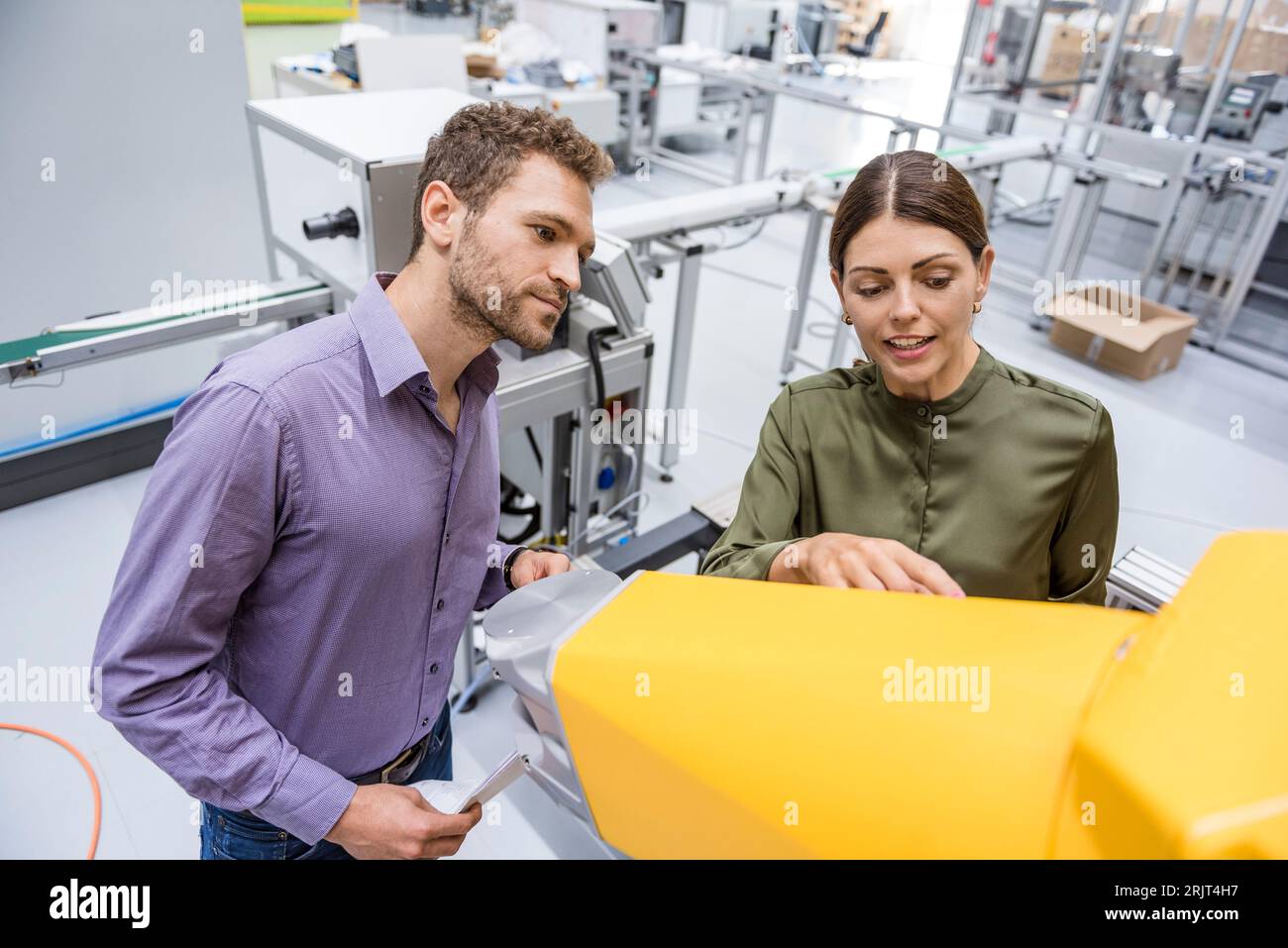 Kaufmann und Frau in einer Sitzung vor Industrieroboter in einem High-Tech-Unternehmen Stockfoto