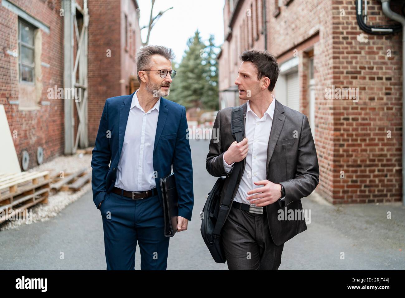 Zwei Geschäftsleute zu Fuß und im Gespräch mit einem alten Backsteingebäude Stockfoto
