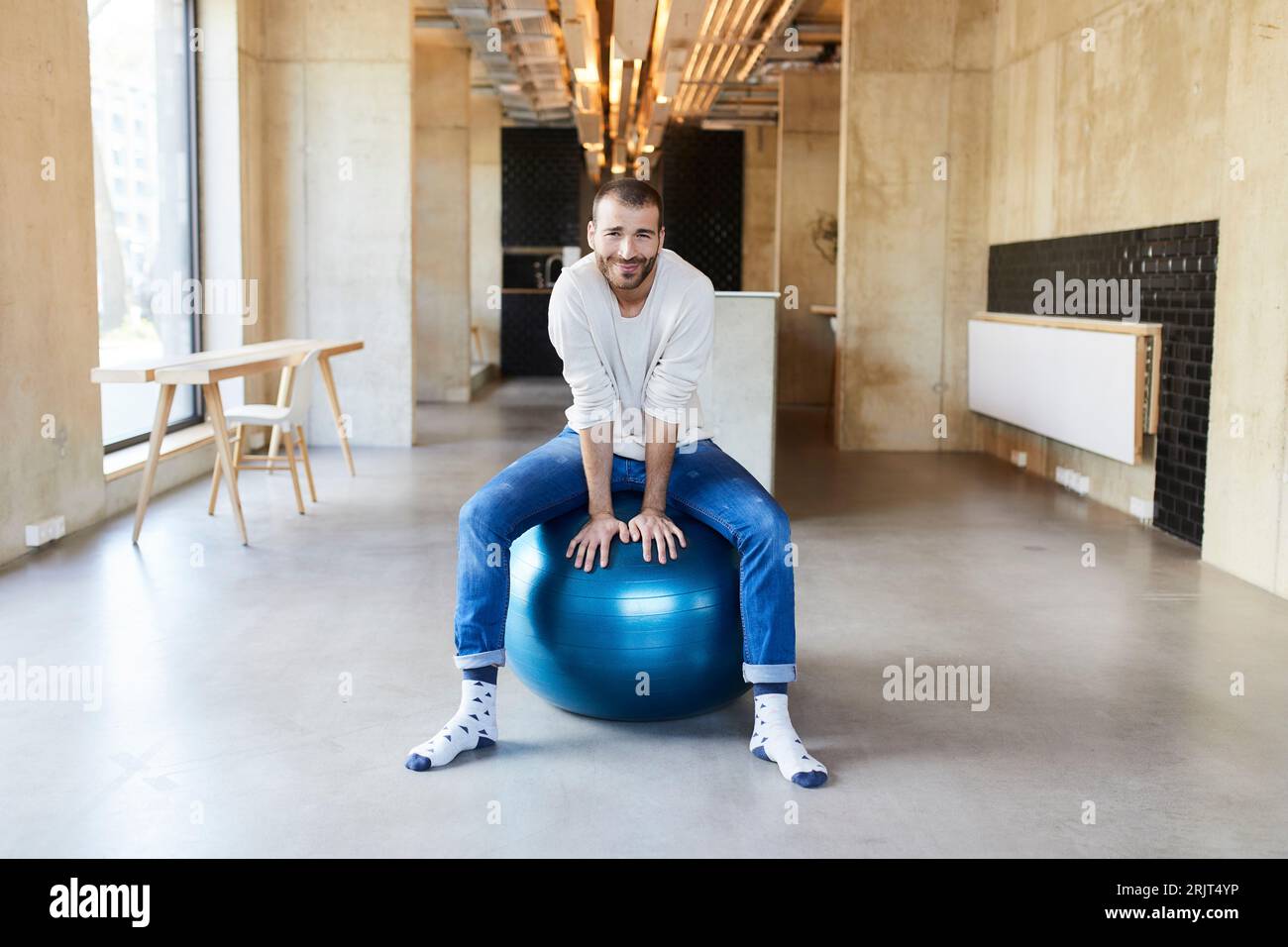 Portrait der junge Mann sitzt auf Fitness Ball in modernen Büro Stockfoto