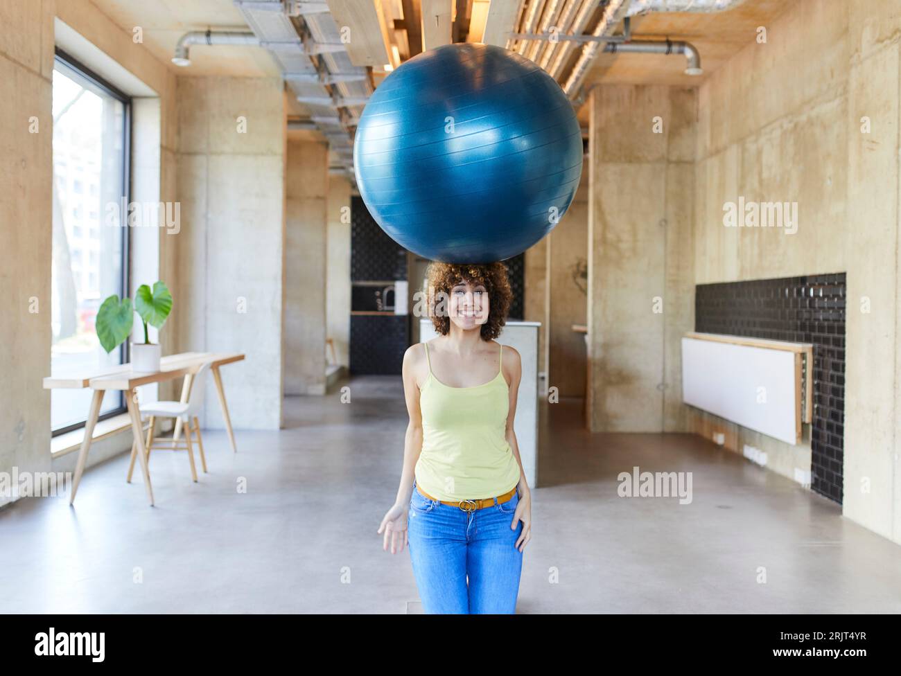 Porträt einer lächelnden Frau, die einen Fitnessball auf dem Kopf balanciert Stockfoto