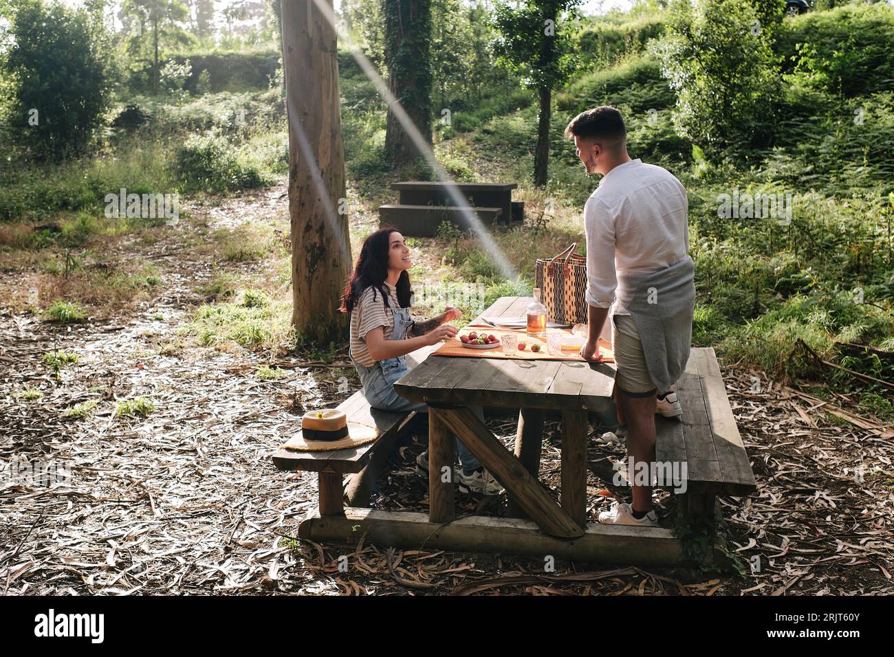 Junges Paar, das Essen auf einer Bank im Wald genießt Stockfoto