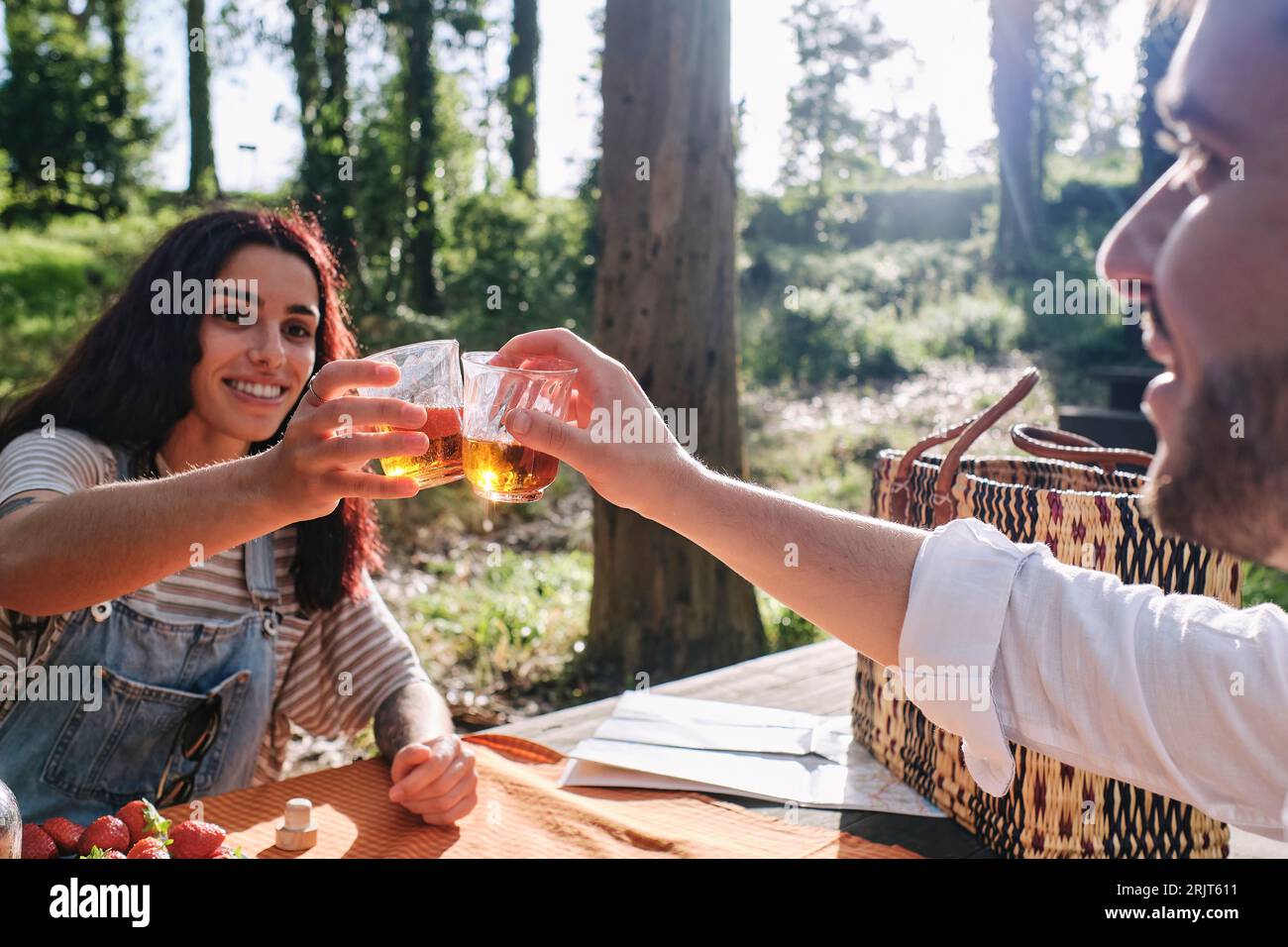 Lächelndes junges Paar, das im Wald trinkt Stockfoto