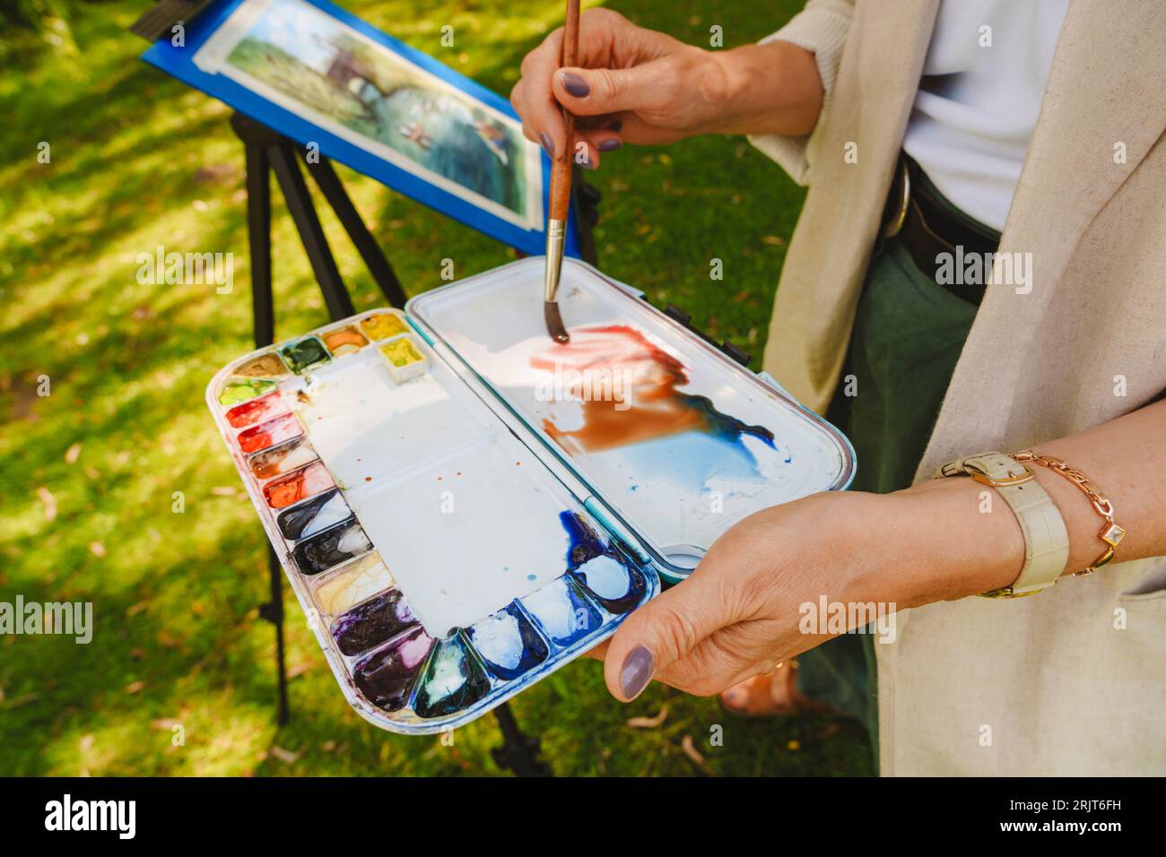 Hände einer Frau mit Aquarellfarben und Pinsel Stockfoto