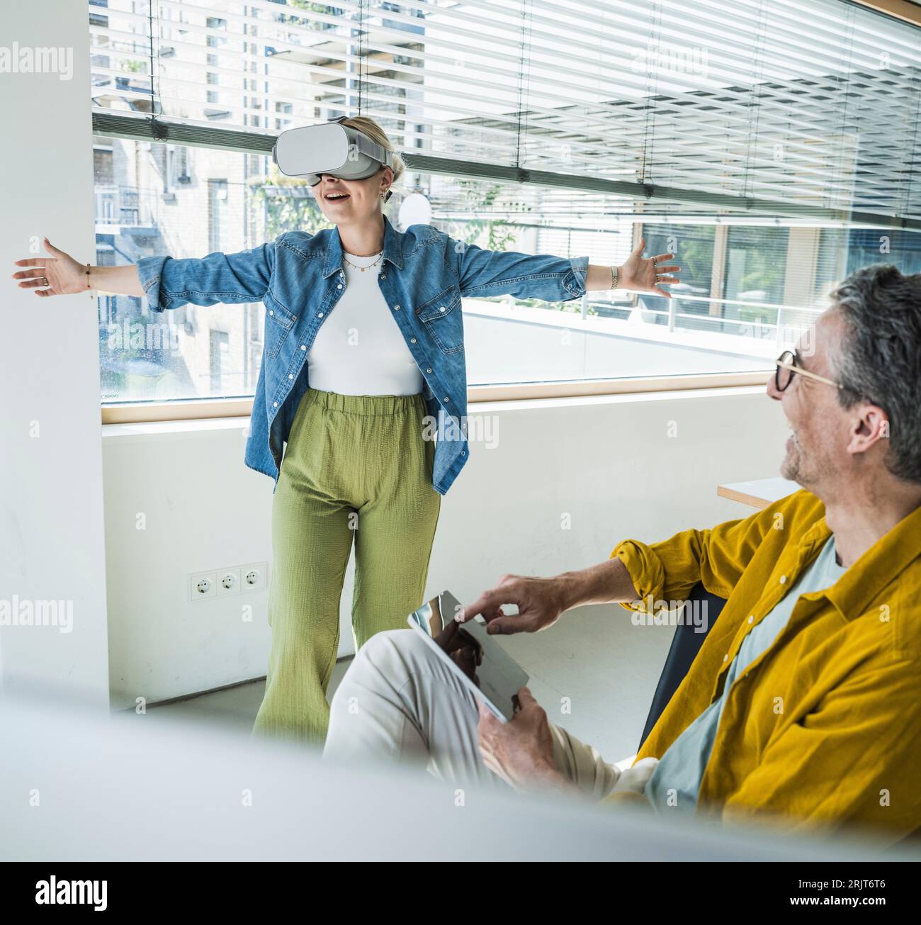 Glücklicher reifer Geschäftsmann mit Kollegen, der Virtual-Reality-Simulatoren im Büro trägt Stockfoto