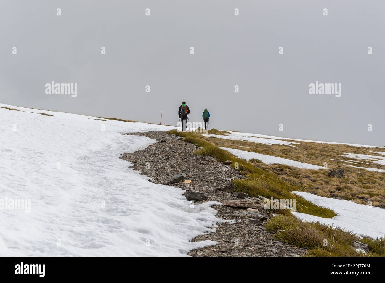 Verschneite Landschaft mit zwei Wanderern, die im Hintergrund in Sierra Nevada spazieren Stockfoto