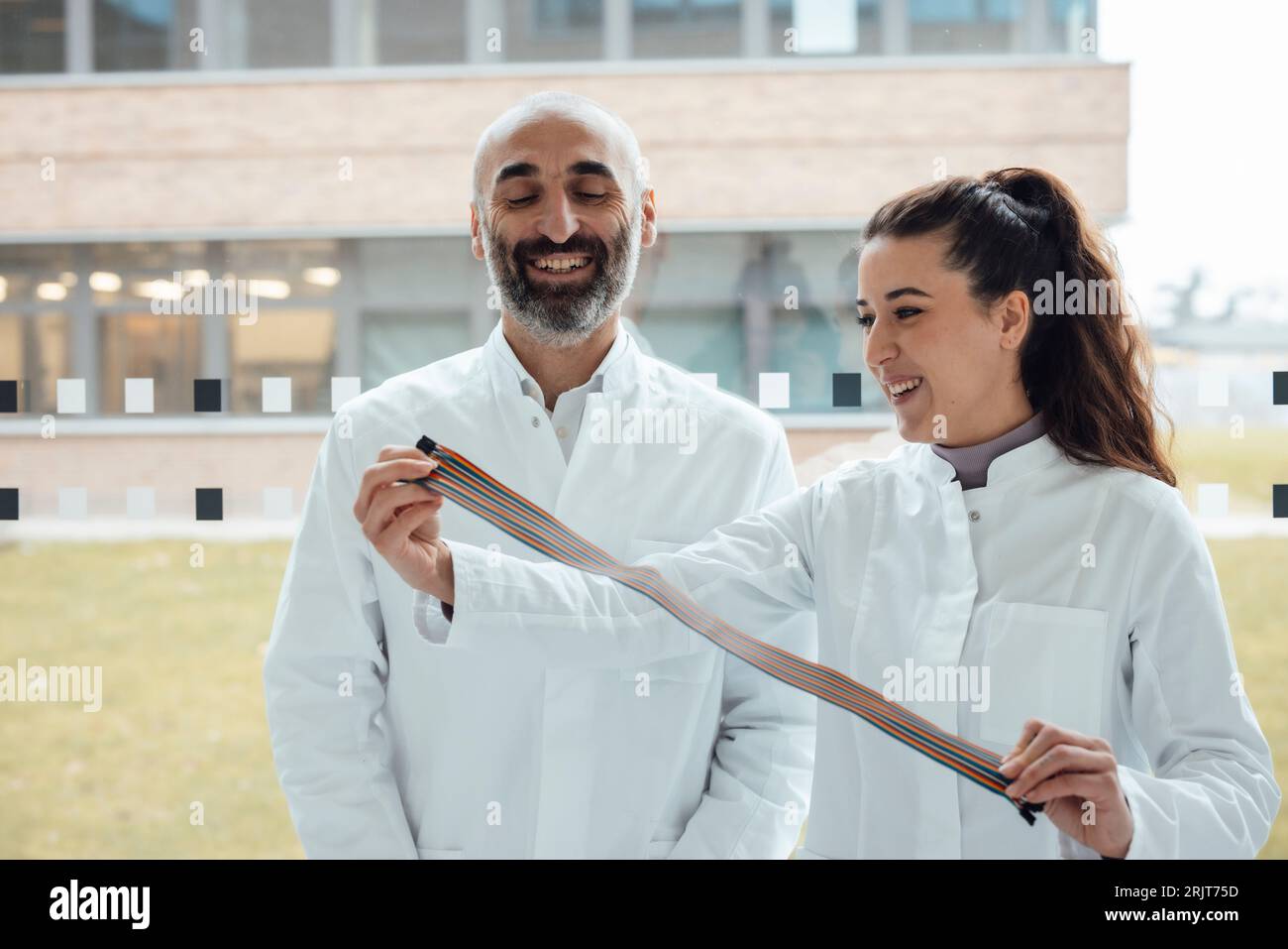 Glückliche Wissenschaftler mit mehrfarbigem Computerkabel Stockfoto