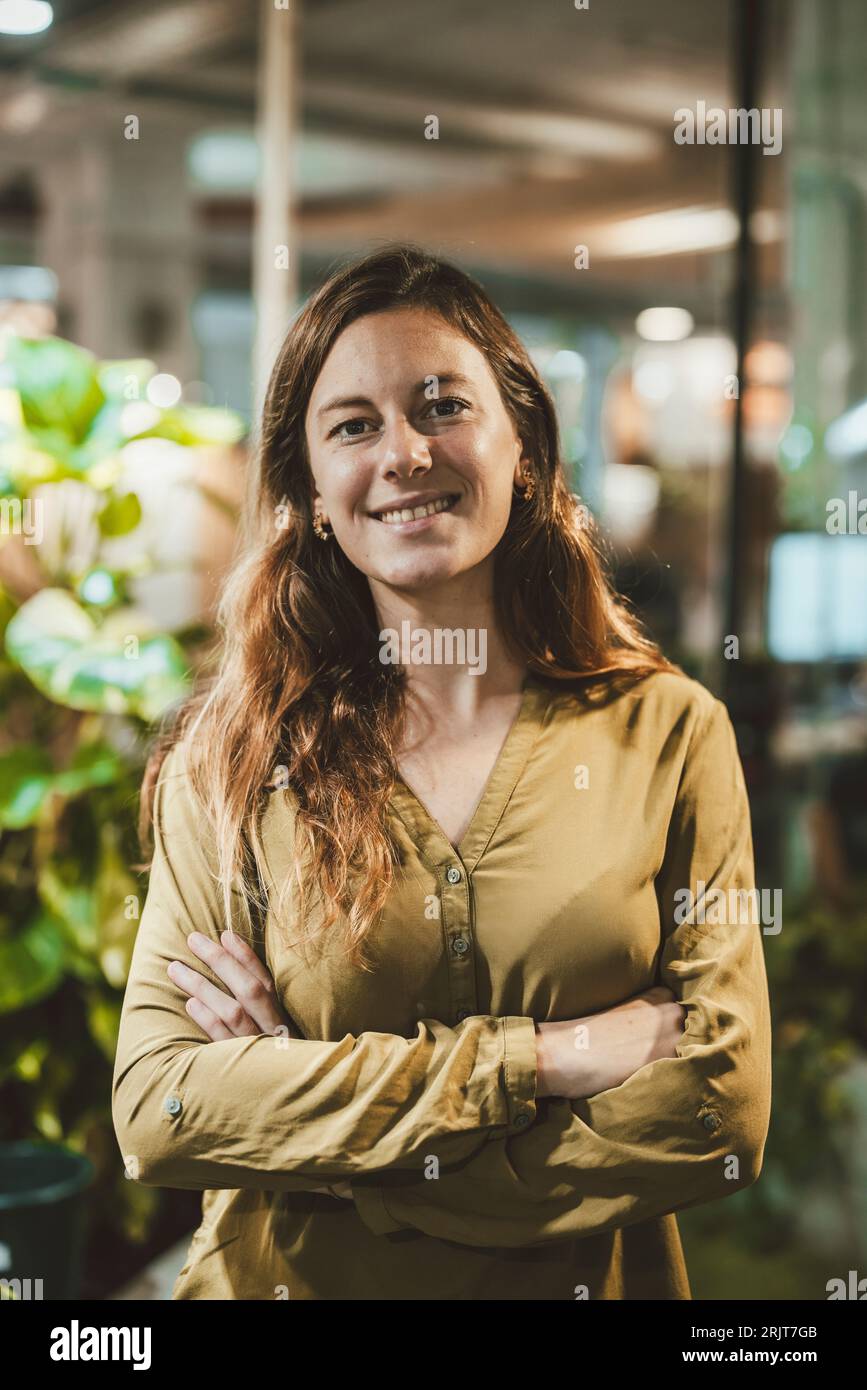 Glückliche Geschäftsfrau mit verschränkten Armen im Amt Stockfoto