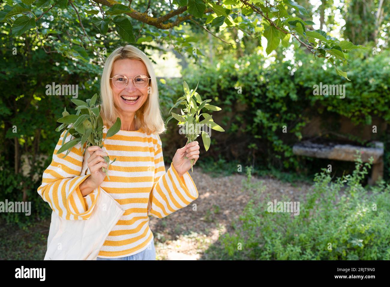 Lächelnde Frau, die Kräuter im Garten hält Stockfoto