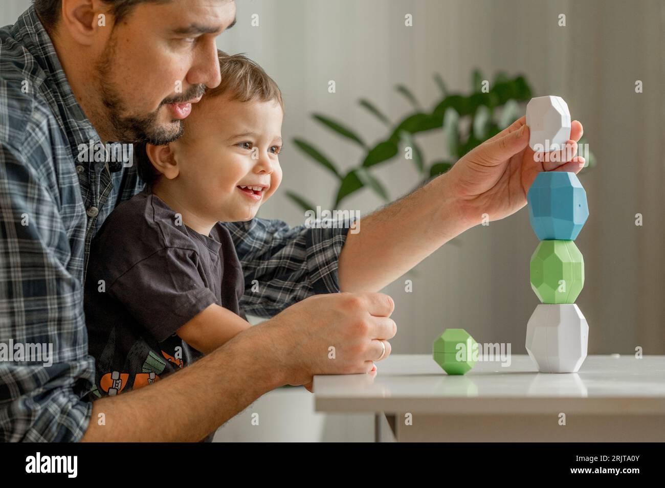 Vater und Sohn bauen zu Hause einen Blockturm Stockfoto