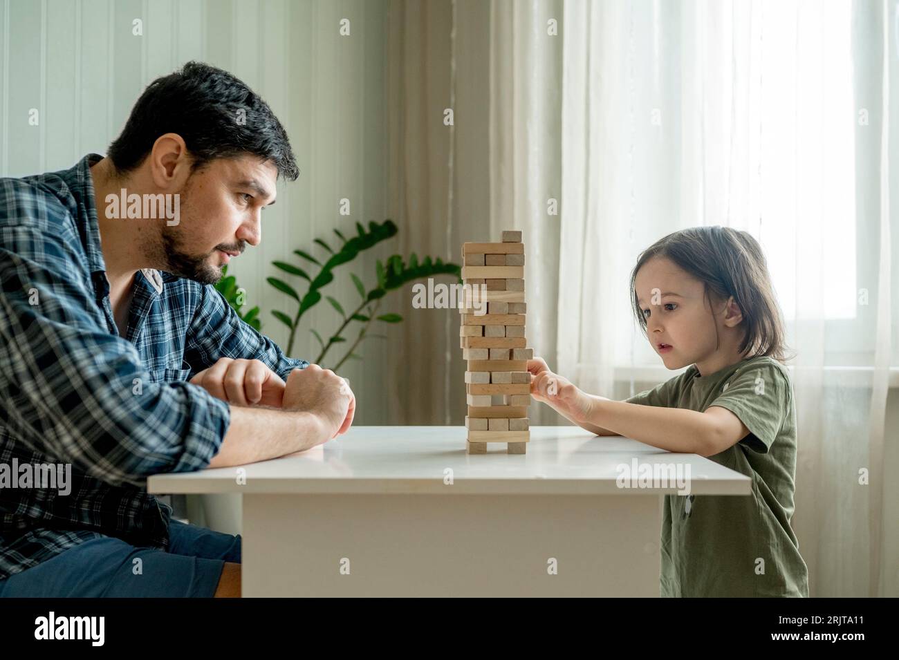 Sohn spielt Jenga mit Vater auf dem Tisch zu Hause Stockfoto