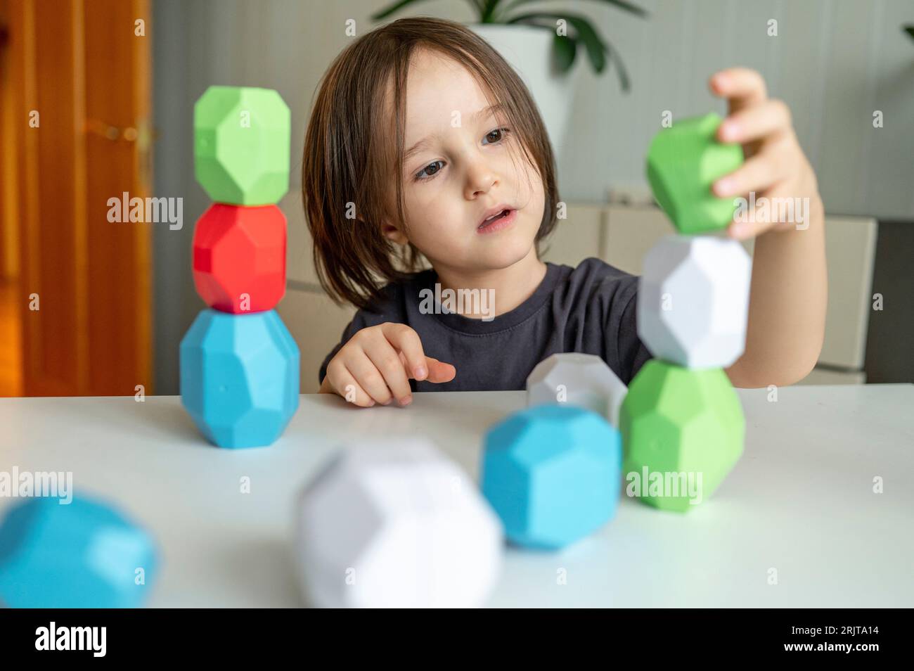 Junge, der zu Hause mit Blocktürmen spielt Stockfoto