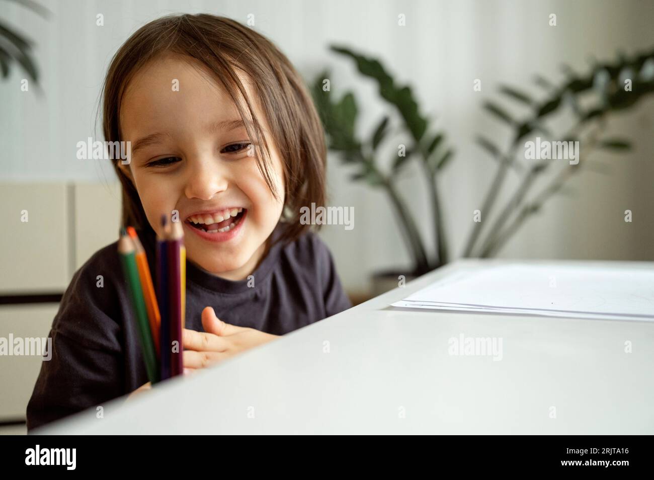 Glücklicher Junge, der sich farbige Bleistifte anschaut Stockfoto