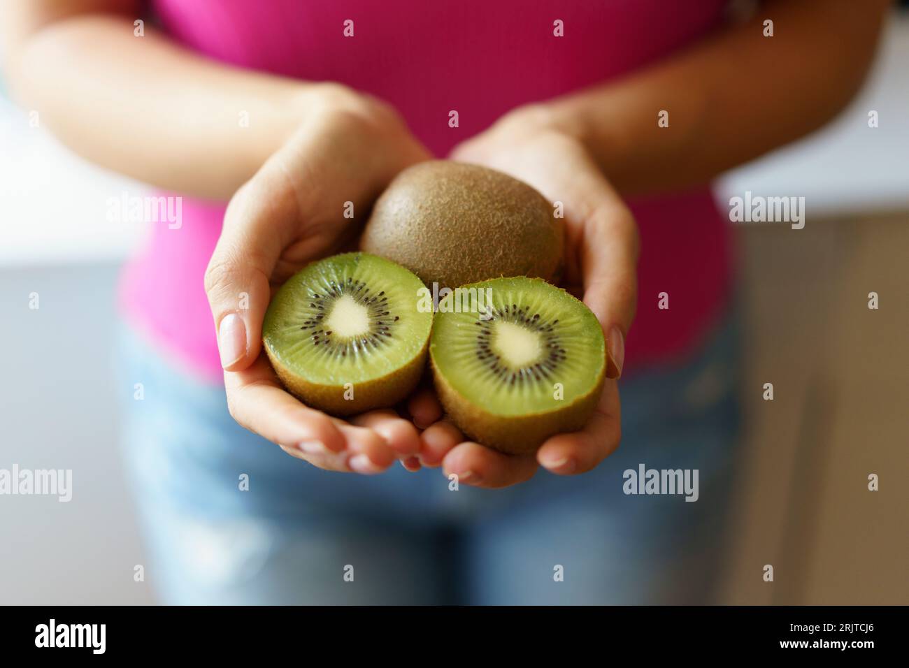 Hände einer Frau, die Kiwifrüchte hält Stockfoto