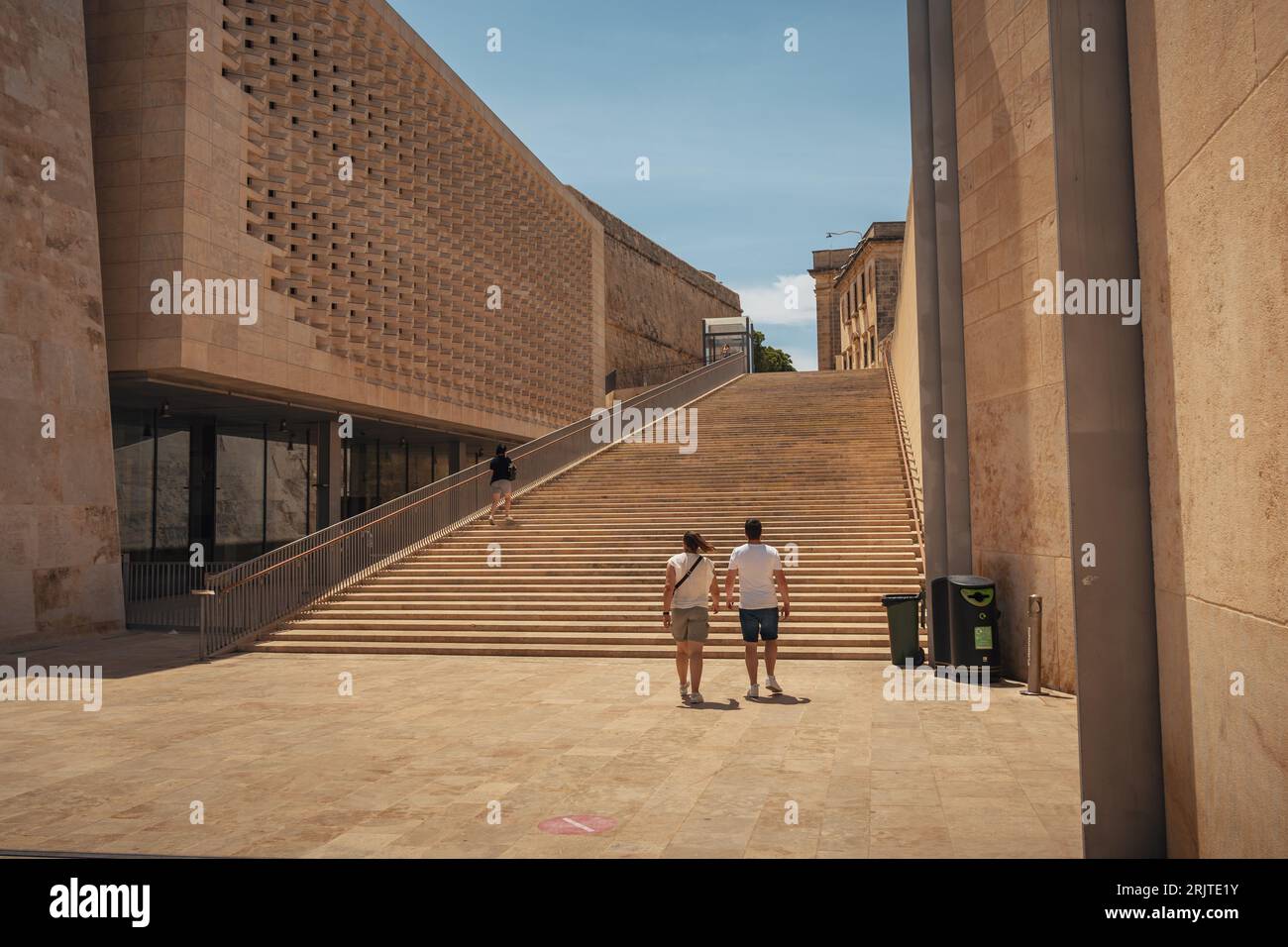 Zwei Personen steigen eine Treppe hinauf, die zu einem majestätischen Bogengang und einem großen Gebäude führt Stockfoto
