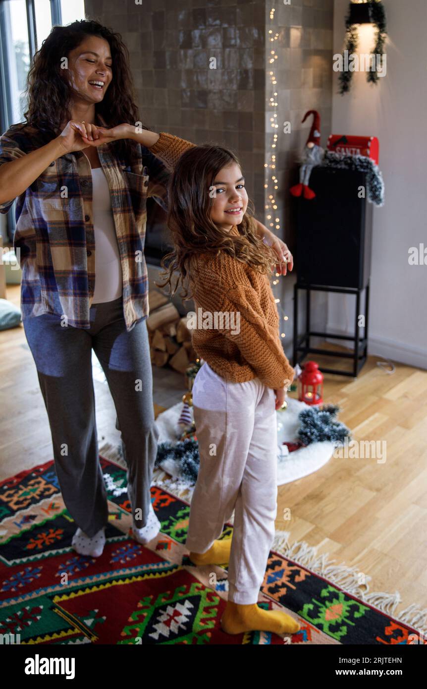 Fröhliche werdende Mutter, die zu Weihnachten mit Tochter zu Hause tanzt Stockfoto