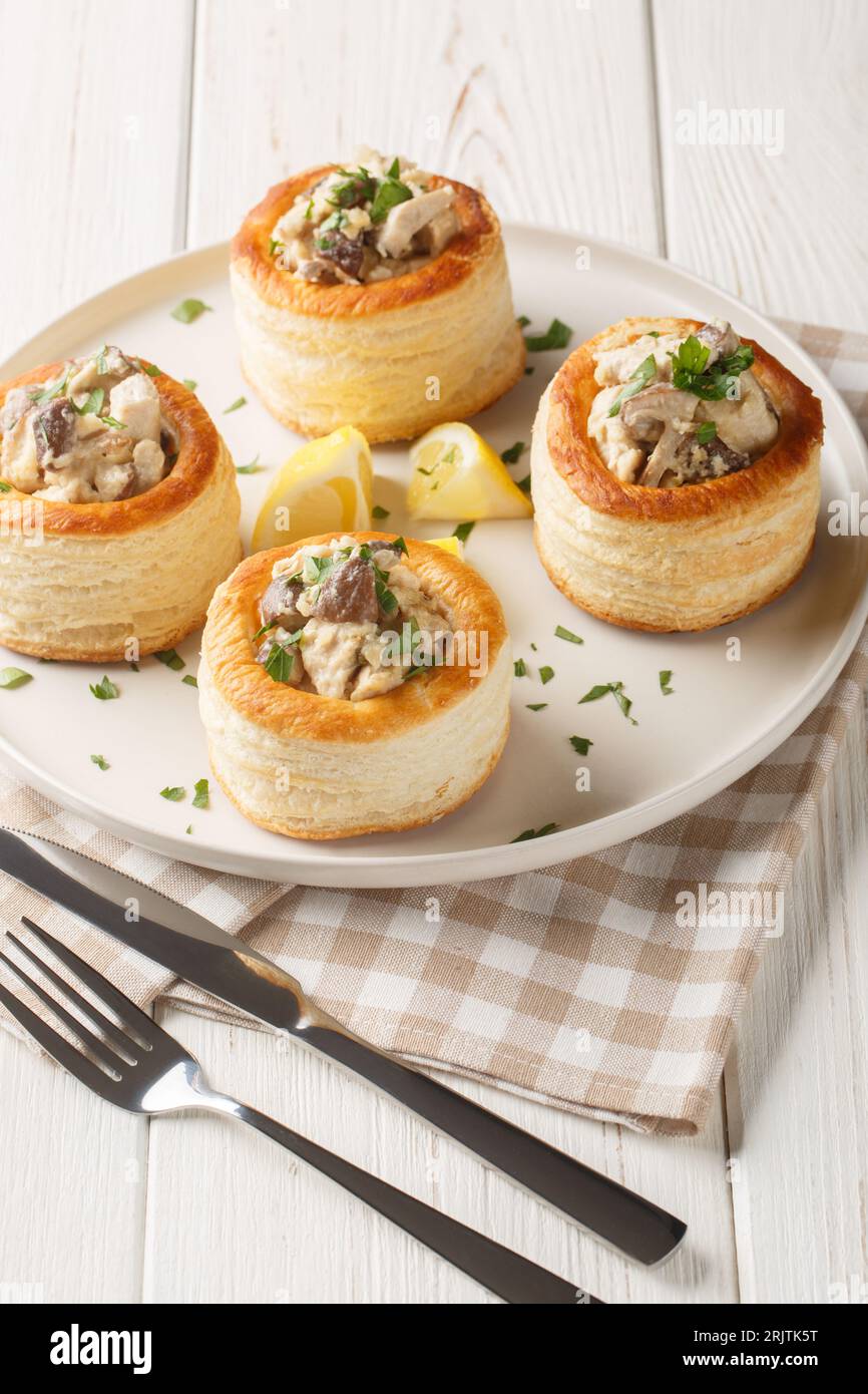 Französische Blätterteigfüllung Vol au Vent mit Hühnchen, Sahne und Pilzcloseup auf dem Teller auf dem weißen Holztisch. Vertikal Stockfoto