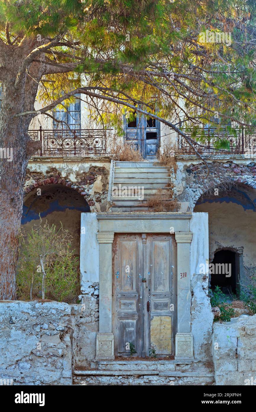 Wunderschönes altes und verlassenes Herrenhaus, mit einer traditionellen Holztür und Treppen, die zum Haupthaus führen, und einem großen Kiefernbaum. Stockfoto