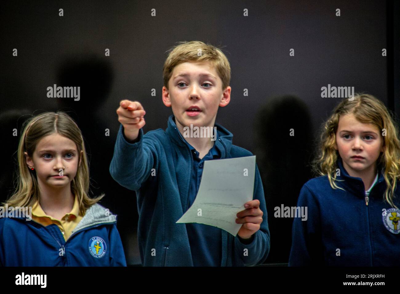 Uniformierte multirassische Schüler einer katholischen Mittelschule in Südkalifornien diskutieren die Bücher, die sie als Gruppe im Klassenzimmer gelesen haben. Stockfoto