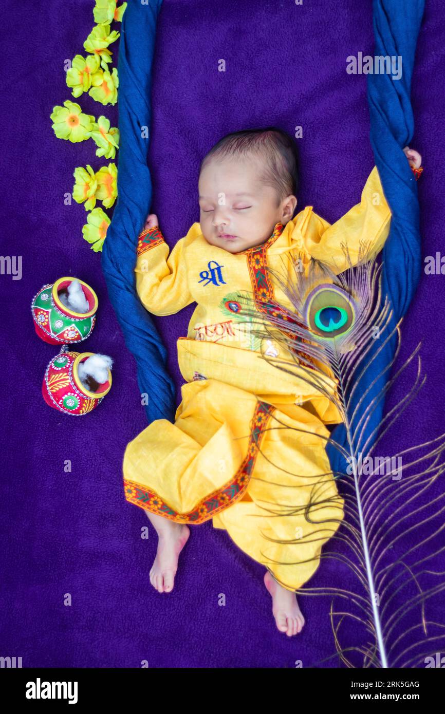 Neugeborener Junge in krishna, gekleidet mit Requisiten im Swing aus einem einzigartigen Blickwinkel in unterschiedlichem Ausdruck Stockfoto